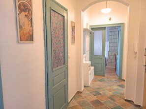 Um corredor com portas estampadas, um aparador branco e piso de azulejos.
