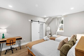 Een moderne hotelkamer met een bureau, twee bedden, een spiegel en een raam.
