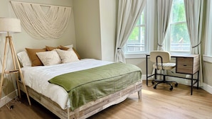 Un dormitorio con una cama de madera, un escritorio y una silla.