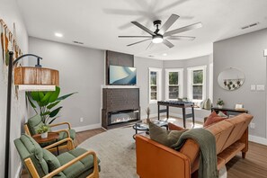 A modern living room with a fireplace, seating area, and a large window.
