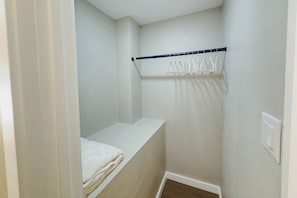Una habitación pequeña y estrecha con una cama individual, una cortina de ducha colgante y un interruptor de luz en la pared.