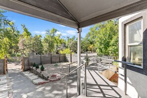 A covered outdoor area with a concrete pathway, metal railings, and a wooden fence. - Traveler’s Dream Home! Hot tub, Firepit, & BBQ (Colorado Springs)