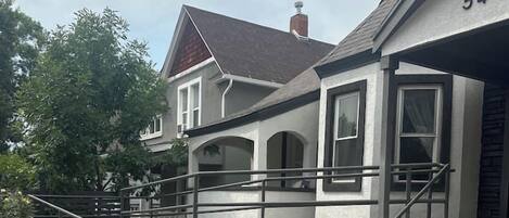 Een woonhuis met een oprit van beton, een trap naar de voordeur en een brievenbus.