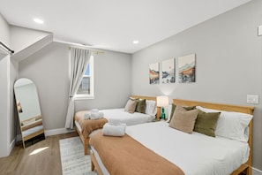 Una habitación de hotel con dos camas, un espejo, una ventana con cortinas y decoración en la pared.