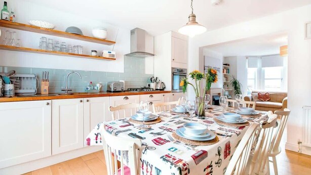 Una cocina moderna con armarios blancos, encimera de madera y comedor listo para una comida.