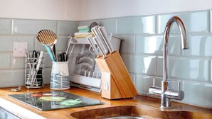 Una encimera de cocina con un lavamanos, un bloque de cuchillos y una tabla de cortar.