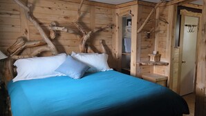 A wooden cabin bedroom with a bed, pillows, and a nightstand. - Modern Suite with Rustic Charm Dog Friendly Suite with King Bed and Full Kitchen (Cedaredge)