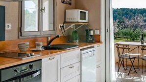 A modern kitchen with white cabinetry, a built-in oven, a microwave, and a coffee maker on the countertop. - Villa Garance with air conditioning (bedroom, living room, and kitchen) (LE BARROUX)