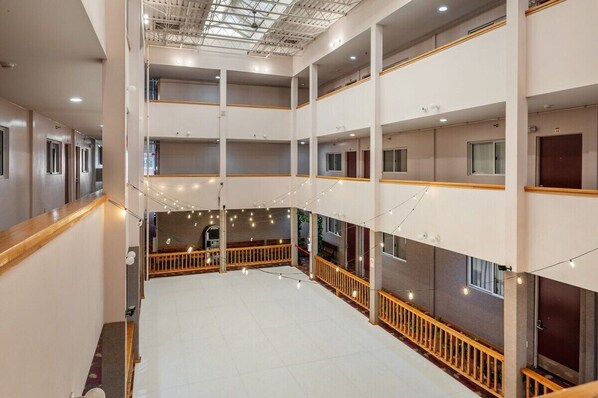 Een hotelinterieur met meerdere niveaus, balkons, lichtslingers en een open centrale ruimte.
