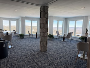 A spacious office with large windows, a stone pillar, and multiple seating areas.