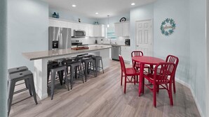 Una cocina moderna con armarios blancos, encimera de granito y una mesa de comedor roja con cuatro sillas.