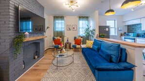 Una sala moderna con un sofá azul, una chimenea y una zona de cocina.