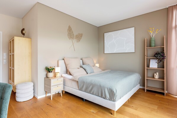 A bedroom with a bed, bedside tables, a wardrobe, and a wall-mounted artwork.