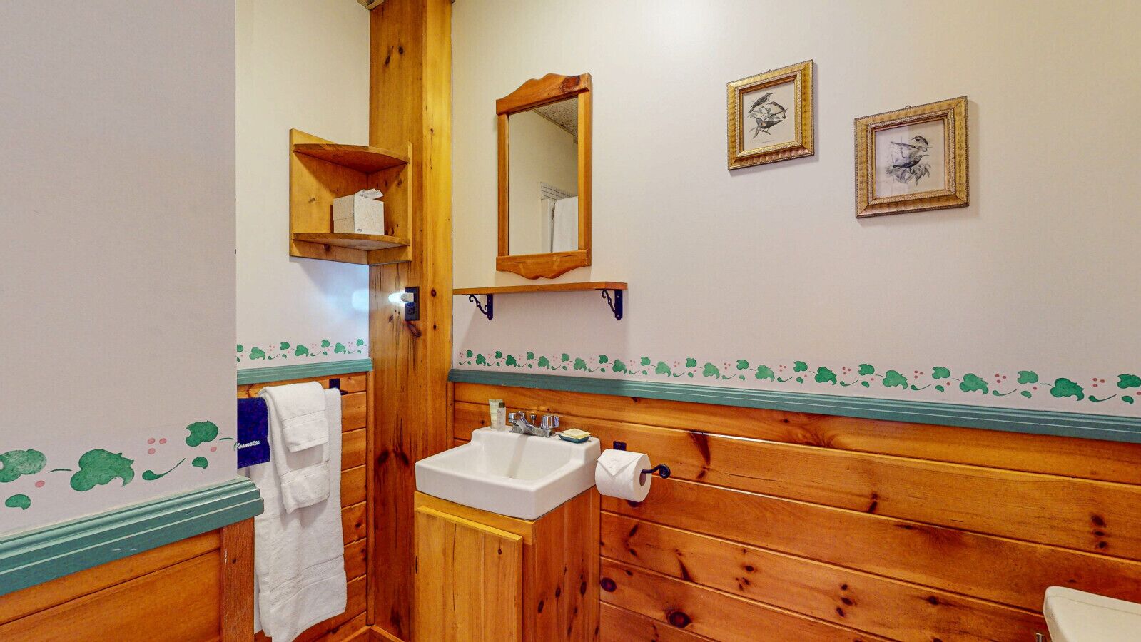 Een houten badkamer met een wastafel, spiegel en handdoekrek.