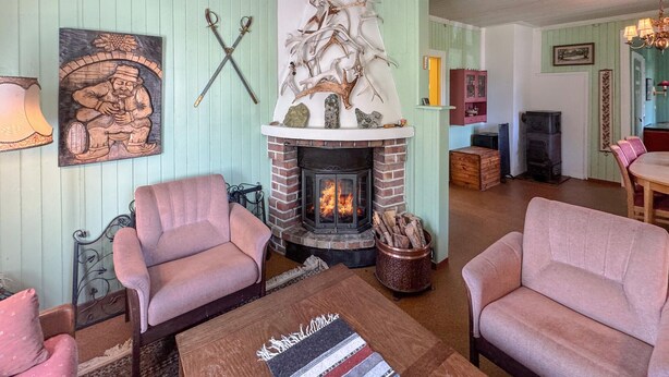 A cozy living room with a fireplace, two armchairs, a coffee table, and a painting on the wall. - Awesome home in Tufsingdalen (Tufsingdalen)