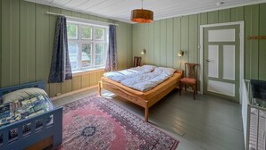 A bedroom with a wooden bed, a window with curtains, a nightstand, a chair, and a door. - Awesome home in Tufsingdalen (Tufsingdalen)