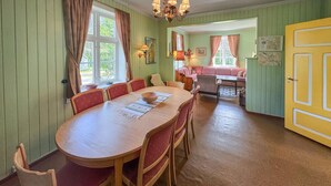 A dining area with a wooden table and chairs, a chandelier, and a yellow door. - Awesome home in Tufsingdalen (Tufsingdalen)