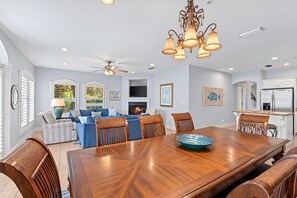 A spacious living room with a fireplace, a dining area with a large wooden table, and a kitchen with modern appliances.