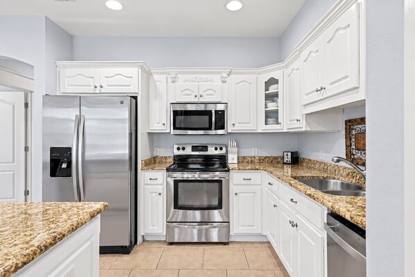 A kitchen with white cabinetry, stainless steel appliances, granite countertops, and a built-in oven.