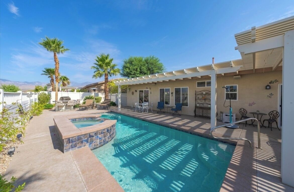 Ein Garten mit Swimmingpool, Terrassenmöbeln und einer Pergola.