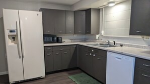 Una cocina moderna con un refrigerador blanco, gabinetes oscuros, un microondas y un lavavajillas.