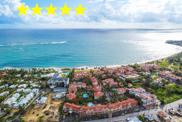 Ein Luftbild eines Küstenresorts mit mehreren Gebäuden, einem Strand und dem Meer.