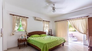 A bedroom with a bed, two nightstands, a ceiling fan, and a window with curtains.