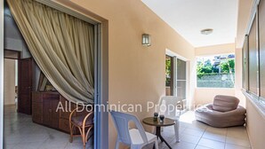 A spacious balcony with a sliding glass door, a small round table, two chairs, and a cushioned seating area.