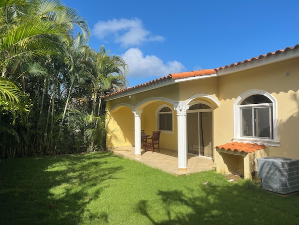 Une maison avec un toit en tuiles, un patio couvert et une pelouse.