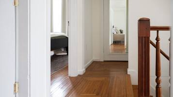 Ein Flur mit Holzboden, weißen Wänden und einer Holztreppe mit Handlauf.