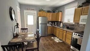 Une cuisine compacte avec des meubles de rangement en bois, un réfrigérateur, un four et une table à manger avec des chaises.
