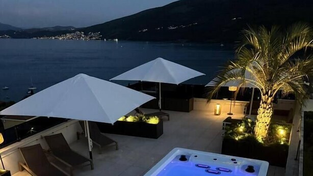 A pool table with a blue light, outdoor seating with umbrellas, and a view of the sea. - Penthouse apartment with sea view and pool area (Đenovići)