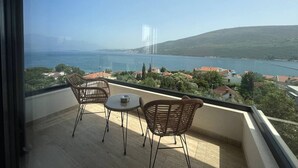 A balcony with wicker furniture and a view of a lake and hills. - Penthouse apartment with sea view and pool area (Đenovići)