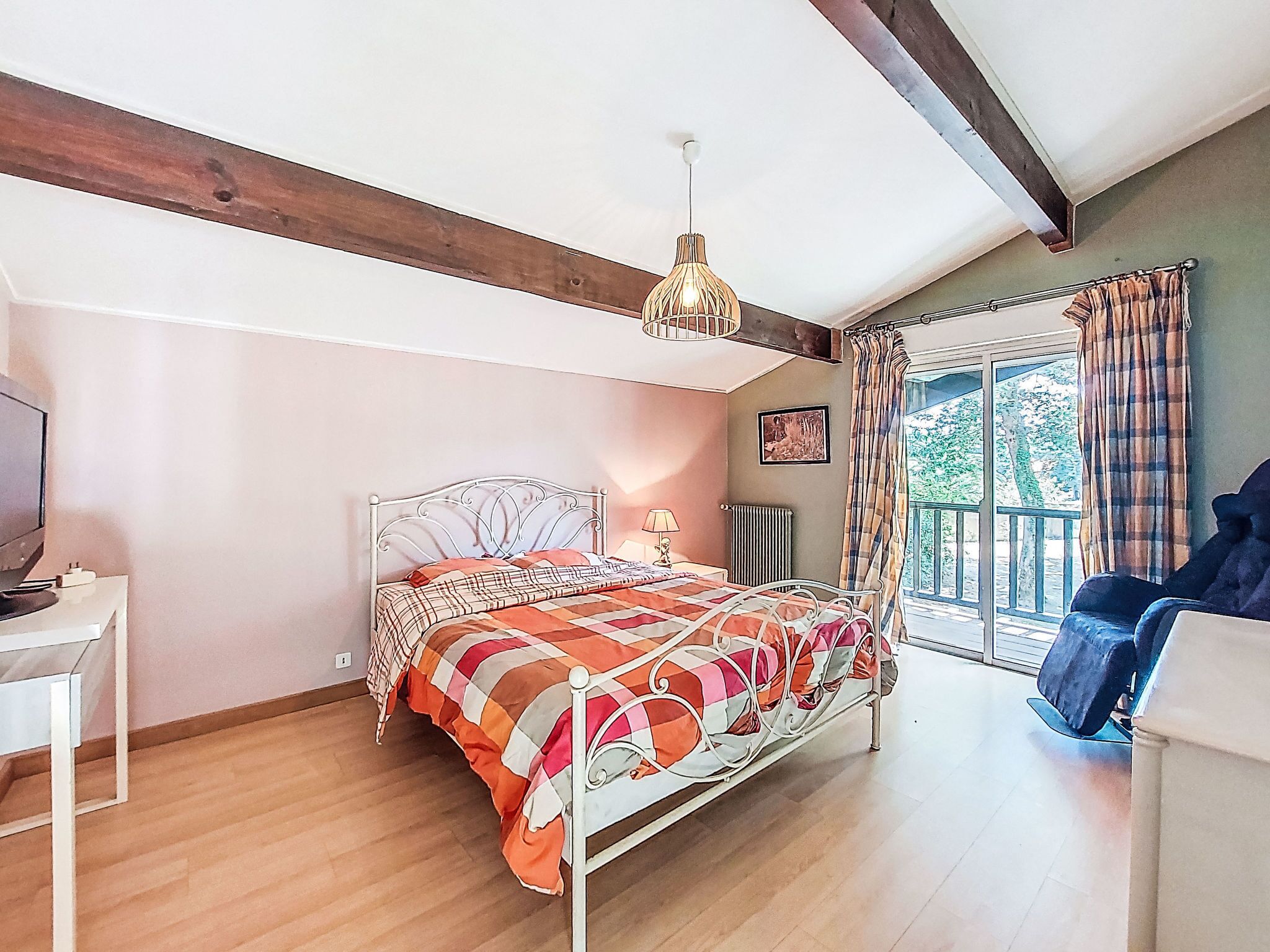 Une chambre à coucher comprenant un lit, un bureau, une chaise, une fenêtre avec des rideaux et un luminaire suspendu.