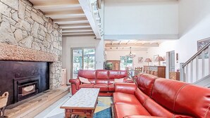 A spacious living room with a stone fireplace, red leather sofa, and a wooden coffee table. - Maison du Chêne Pointu by Interhome (Saint Pandelon)