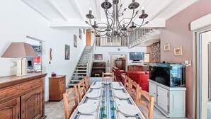 A dining area with a long table set for six, a chandelier, and a staircase leading to an upper level. - Maison du Chêne Pointu by Interhome (Saint Pandelon)