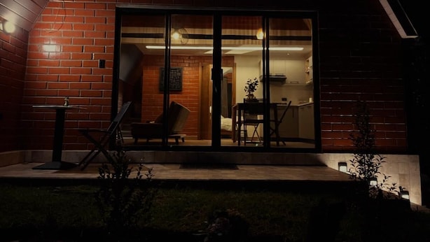 A modern house with a brick exterior, a glass door entrance, and a small patio with outdoor furniture. - El Alba Descanso (Patate)