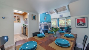 Un comedor con una mesa de madera dispuesta para seis, platos azules y un jarrón con flores blancas.
