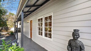 A house with a covered porch, white siding, and a statue of a warrior.