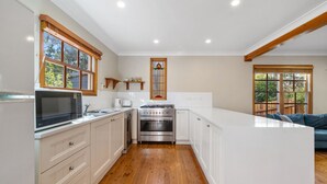 A modern kitchen with white cabinets, a stainless steel stove, and wooden flooring.