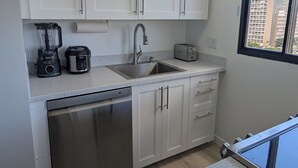 A modern kitchen with white cabinets, a stainless steel dishwasher, a coffee maker, and a toaster. - Newly renovated, secure, 2-bedroom apartment in beautiful Waikiki with AC (Honolulu)