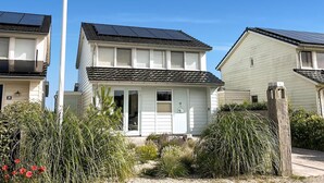 Un immeuble résidentiel doté de panneaux solaires sur le toit, d’une porte d’entrée et d’un petit espace porche.