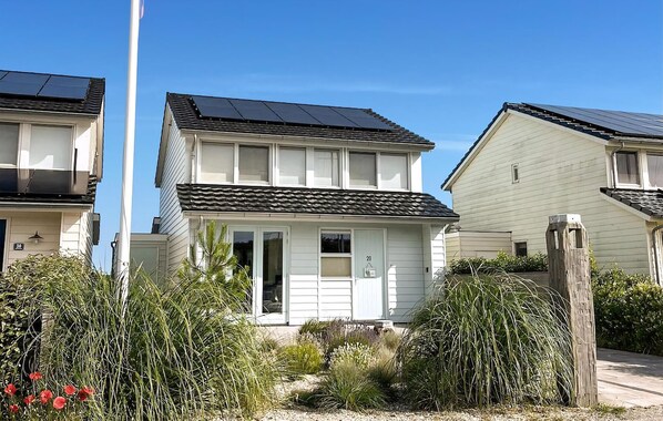 Un immeuble résidentiel doté de panneaux solaires sur le toit, d’une porte d’entrée et d’un petit espace porche.