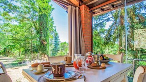 A table set for breakfast with a view of trees and a brick wall. - Rifugio di Igor by Interhome (Montecatini Terme)