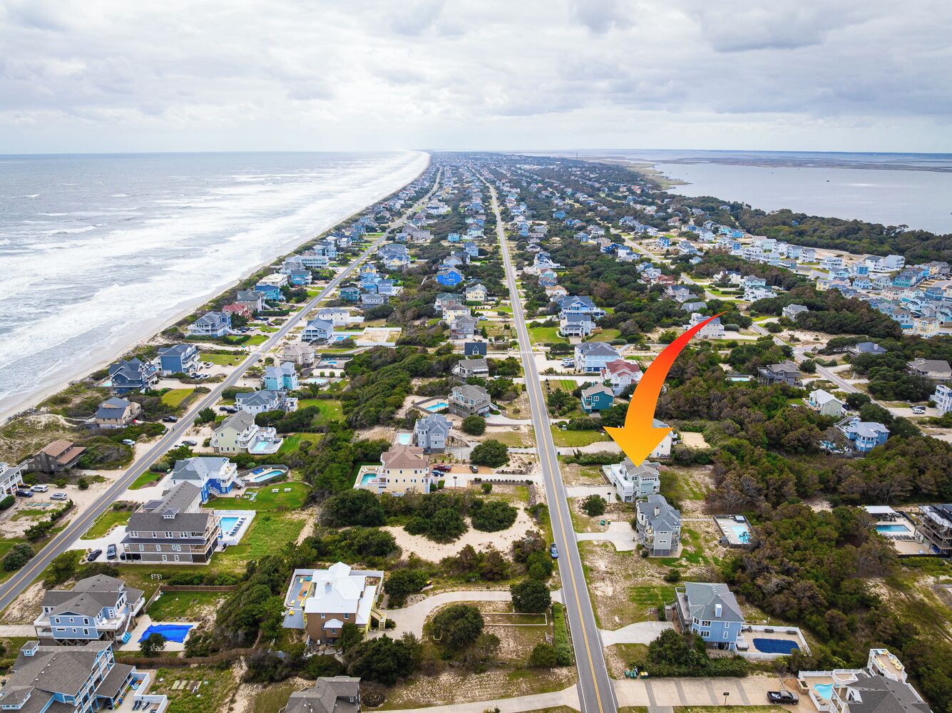 An aerial view of a coastal residential area with houses, roads, and a beach.
