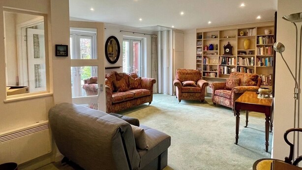A cozy living room with a fireplace, a bookshelf, and comfortable seating. - Farnham Haven: Unique Home with Courtyard (Farnham)