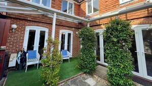A two-story brick house with a small garden, a white door, and a blue chair. - Farnham Haven: Unique Home with Courtyard (Farnham)