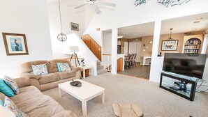 A living room with a sofa, coffee table, and TV stand. There is a staircase leading to another room. - Resort Amenities, Community Pools, Hot Tub-645, Cohasset II (Corolla)