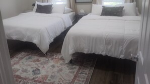 Quarto com duas camas de solteiro, um espelho grande e uma janela com cortinas.
