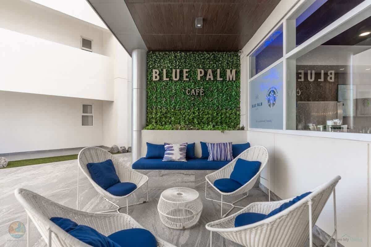 Un café Blue Palm avec des meubles en osier et un mur recouvert de verdure.